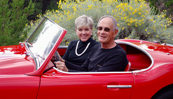 Eric and Deborah sitting in a red convertible